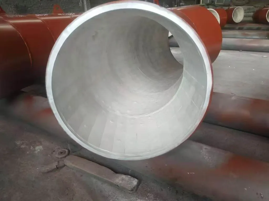 Open end of an alumina ceramic-lined elbow showing the segmented tile lining with visible joints inside the steel shell