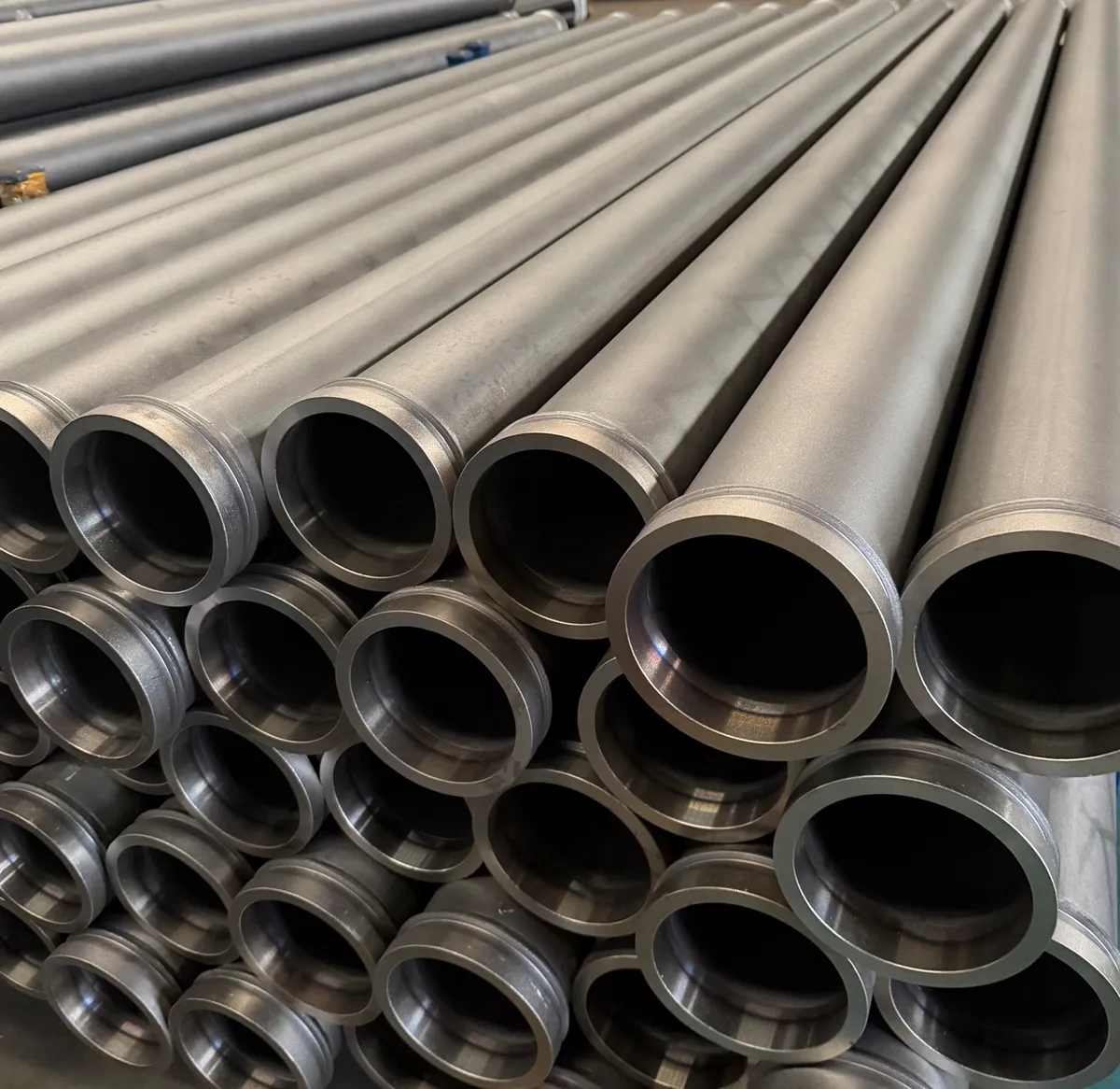 16Mn steel pipe ends stacked in layers with the machined end faces toward the camera, showing turned rims and dark bores