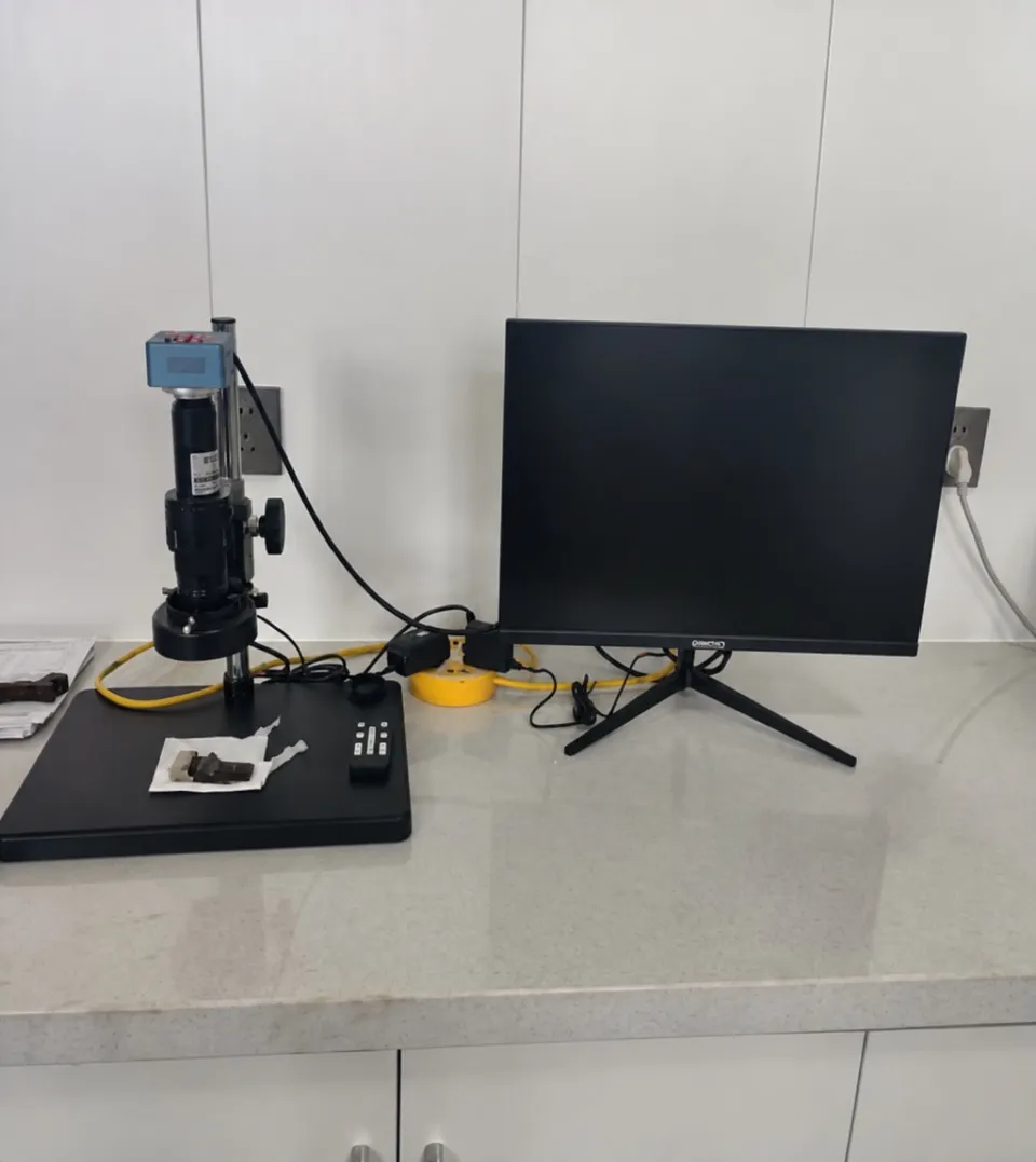 Digital microscope on its stand facing a monitor on the bench