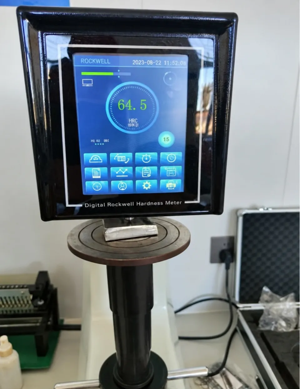 Digital Rockwell hardness tester with its touchscreen display above the testing stage