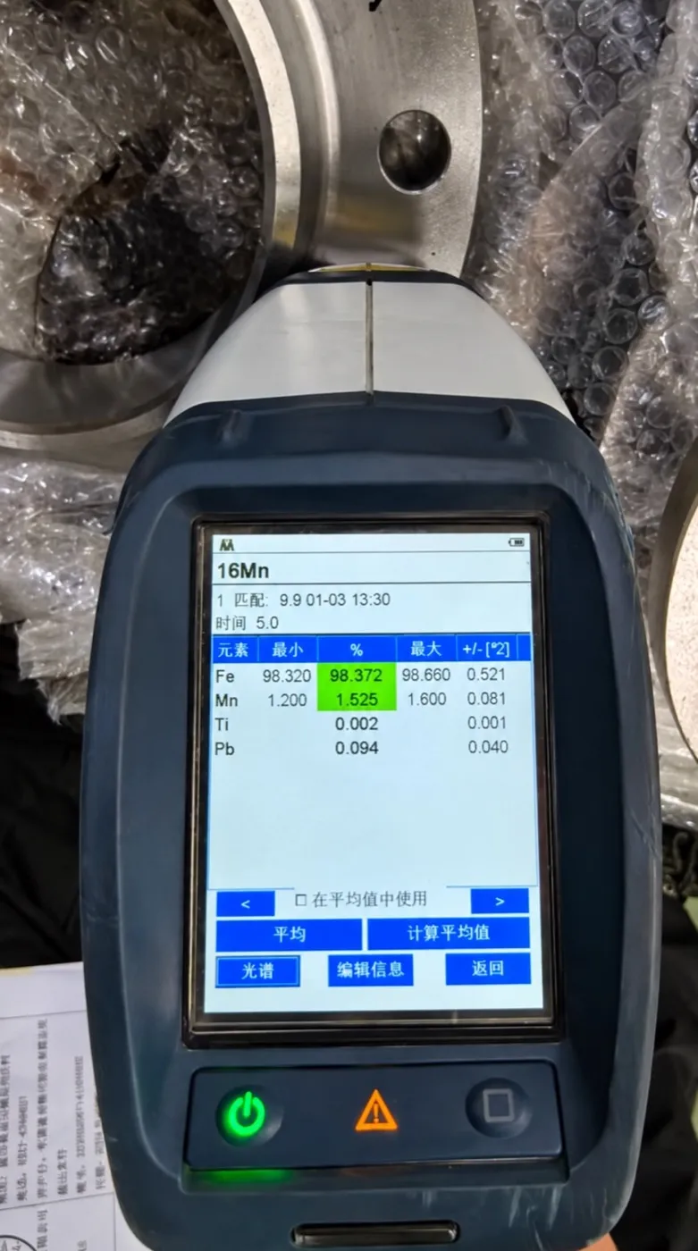 Handheld alloy analyzer held against a machined metal part, with the analysis shown on its screen