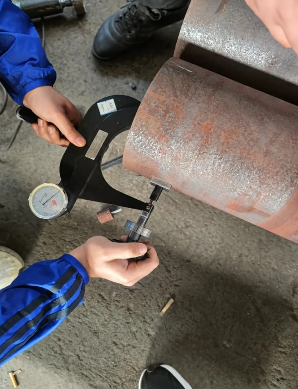 Portable hardness tester in use on a large steel pipe in the workshop