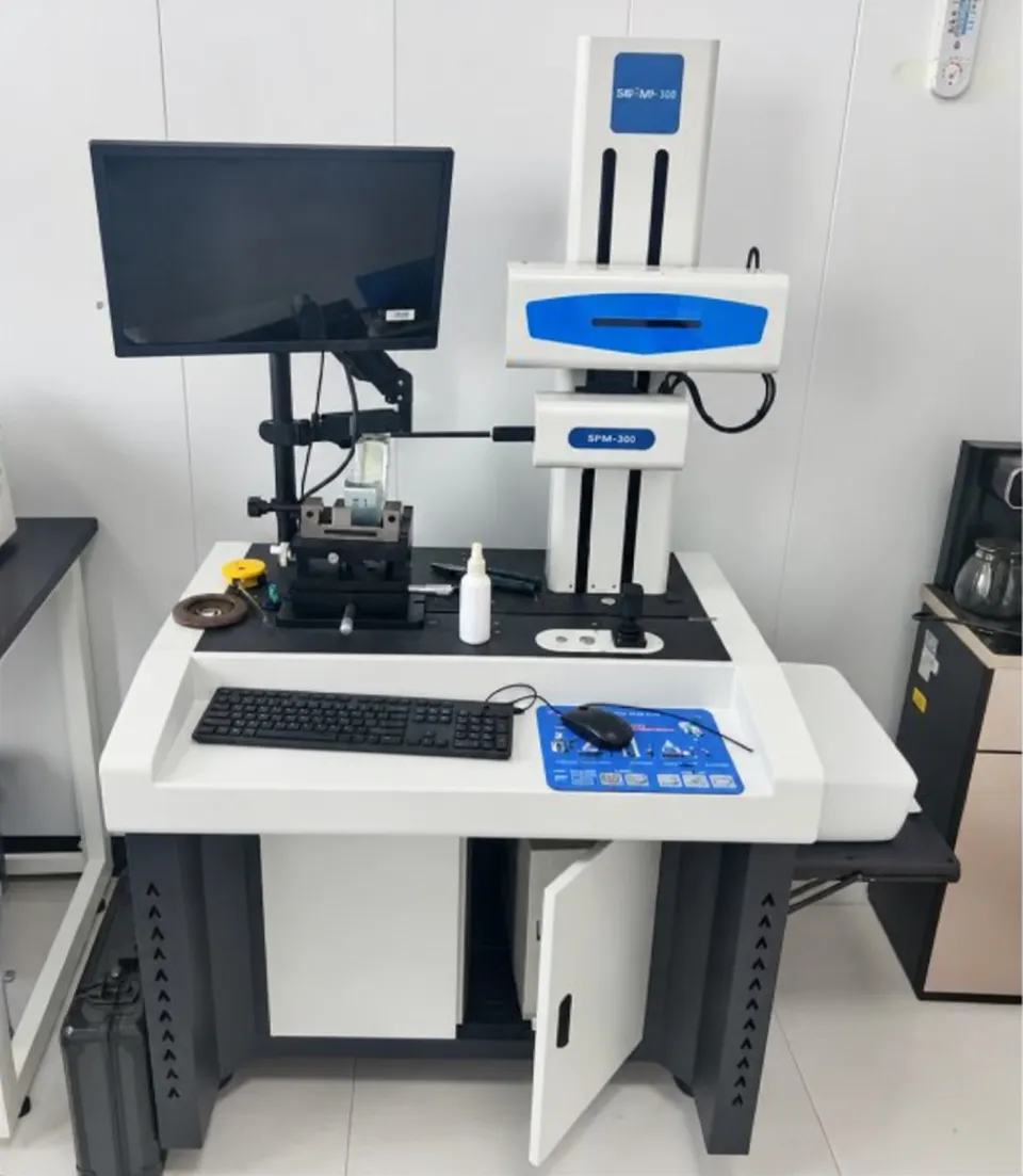 Measuring column with a display and a stage on a laboratory bench, with a monitor on an arm beside it